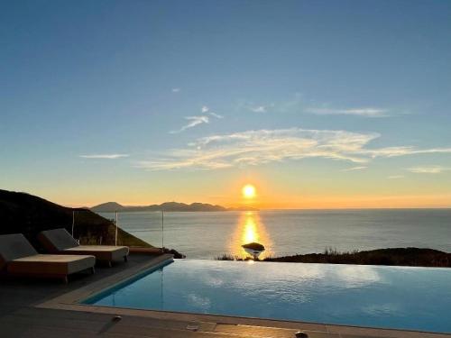 a swimming pool with a view of the ocean at sunset at Entheos Private Villa Fiskardo Kefalonia Greece in Fiskardho