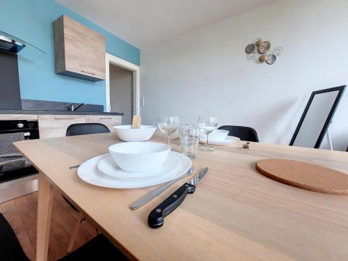 a wooden table with plates and bowls and wine glasses at LE CARILLOUN in Mirande