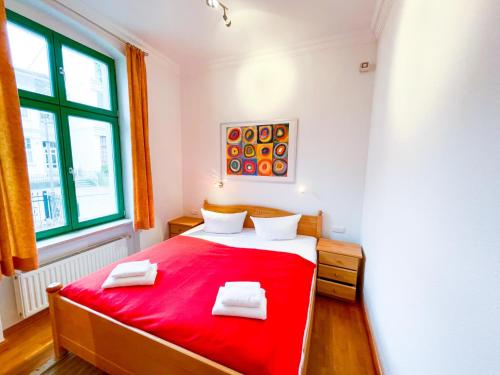 Un dormitorio con una cama roja con dos toallas encima. en Villa Perkunos Wohnung Nr. 6, en Heringsdorf
