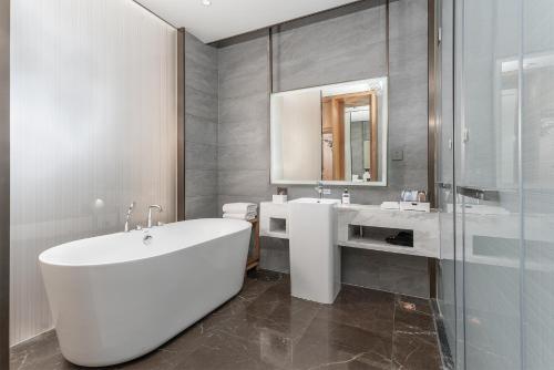 ein Badezimmer mit einer großen weißen Badewanne und einem Waschbecken in der Unterkunft Holiday Inn Express Pingchang, an IHG Hotel in Bazhong