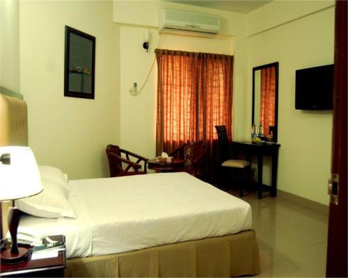 Habitación de hotel con cama, mesa y escritorio. en Ambassador en Chittagong