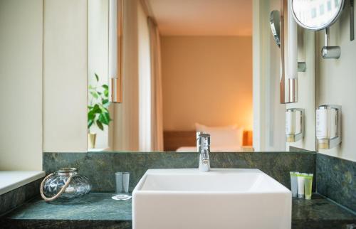 a bathroom with a white sink and a mirror at Lindner Hotel Berlin Ku'damm, part of JdV by Hyatt in Berlin