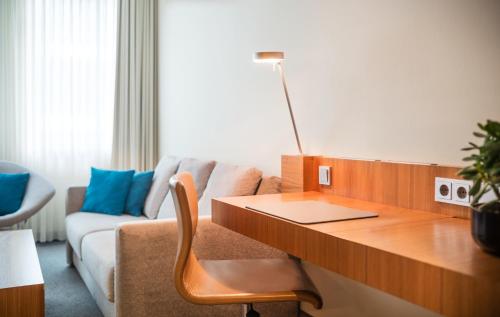 a living room with a desk and a couch at Lindner Hotel Berlin Ku'damm, part of JdV by Hyatt in Berlin