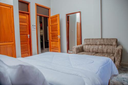 ein Schlafzimmer mit einem Bett und einem Stuhl in der Unterkunft Mahogany Mine Apartments-3 in Daressalam