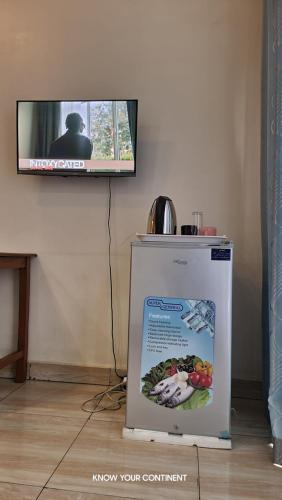 a flat screen tv on a wall with a refrigerator at Puma Aparthotel - Nyarutarama in Kigali