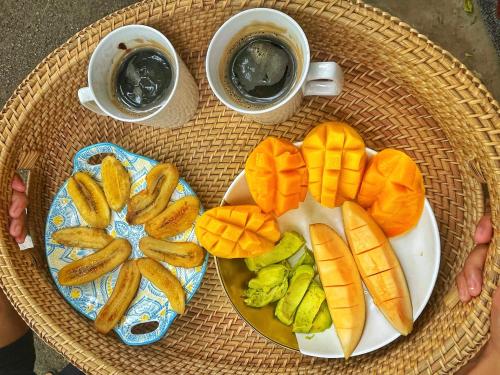 une table avec deux assiettes de fruits et deux tasses de café dans l'établissement Loko Amigos Bohol Panglao, à Mormol