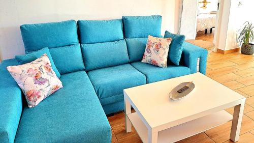 a blue couch with two pillows and a table at Luna Nueva con Jacuzzi in Tarajalejo