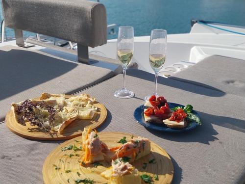 two plates of food and glasses of wine on a table at Private Exclusive Catamaran 'Hang Loose' in Barcelona