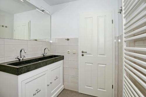 La salle de bains blanche est pourvue d'un lavabo et d'un miroir. dans l'établissement Villa Hanse Wohnung 313, à Kühlungsborn