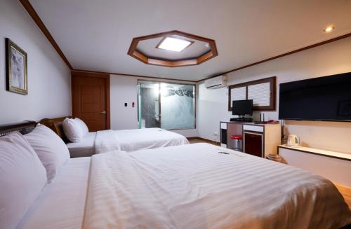 a hotel room with two beds and a flat screen tv at Buantreehotel Blackhouse in Buan
