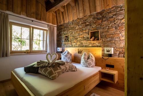 een slaapkamer met een bed met een bakstenen muur bij Wochenbrunner Chalets in Ellmau