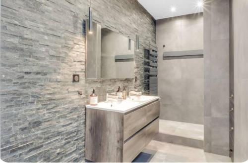 baño con lavabo y pared de piedra en Appartement Luxe- Terrasse Unique, en Neuilly-sur-Seine