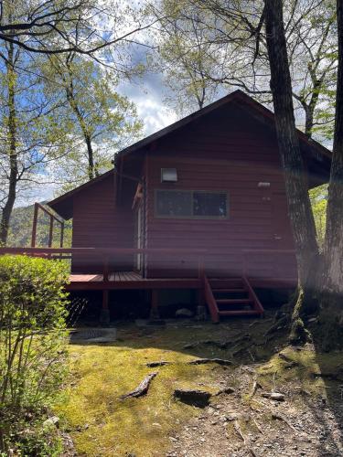 a red cabin with a porch in the woods at Jomine Koen Campjo - Vacation STAY 85267v in Minano