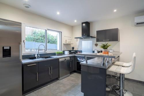 d'une cuisine avec des placards noirs, un évier et une fenêtre. dans l'établissement L'Escapade du Petit Mas - Appt climatisé, à Nexon