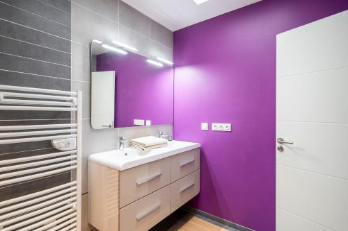 La salle de bains violette est pourvue d'un lavabo et d'une douche. dans l'établissement L'Escapade du Petit Mas - Appt climatisé, à Nexon