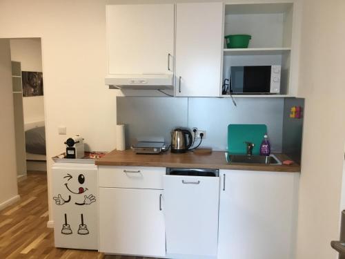 eine kleine Küche mit weißen Schränken und einem Waschbecken in der Unterkunft Sieveringer A-B in Wien
