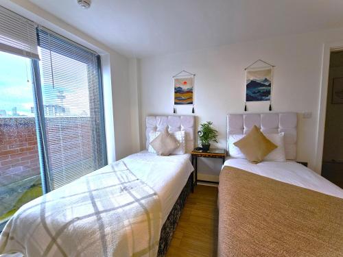 two beds in a room with a window at Lovely Central 1-Bedroom Flat with a View, Ideal Getaway in Liverpool