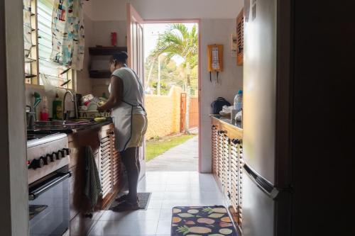 una mujer parada en una cocina preparando comida en Bonnen Kare en Grand Anse