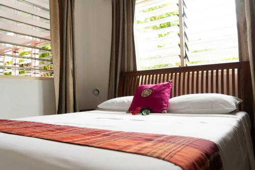 ein Bett mit einem lila Kissen darüber in der Unterkunft Bonnen Kare in Grand Anse