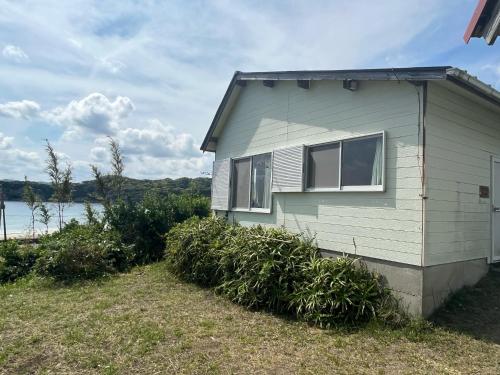 a small house with bushes next to a body of water at Yotsubaso Bungalow Village - Vacation STAY 85280v in Moriya