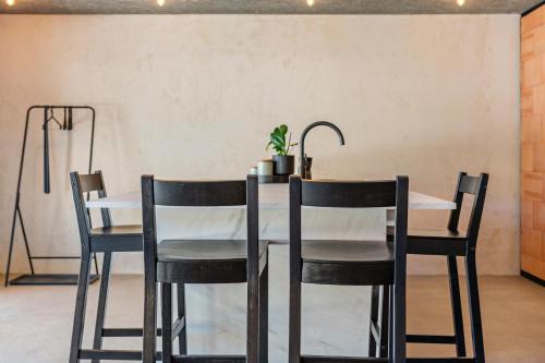 a dining room table with black chairs and a white table at Lena Dolomites Gartensuite in Villnoss
