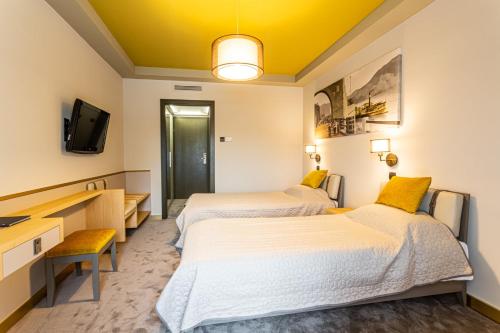 a hotel room with two beds and a tv at Hotel Visegrád in Visegrád