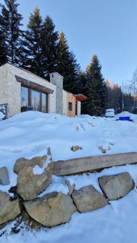 a snow covered yard with rocks and a building at Babiogórskie Domki in Lipnica Wielka