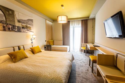 a hotel room with a bed and a flat screen tv at Hotel Visegrád in Visegrád