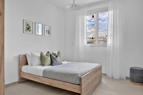 Un dormitorio con una cama con paredes blancas y una ventana en Phaedrus Living: Eolus Residences Hera, en Strovolos