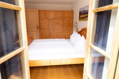 a bed in a room with two windows at Fewo Schönes Ammertal in Oberammergau