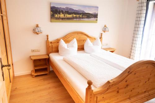 sypialnia z drewnianym łóżkiem z białą pościelą w obiekcie Fewo Schönes Ammertal w mieście Oberammergau