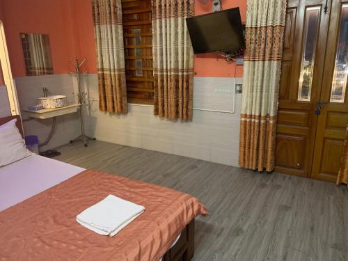 um quarto com uma cama, uma televisão e cortinas em Khách sạn minion 2 em Thuan An