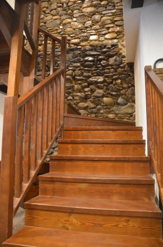 a set of wooden stairs in front of a stone wall at Casa Sapita in Villafranca del Bierzo