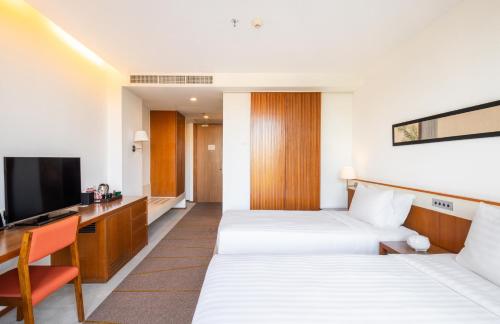a hotel room with two beds and a television at Eastin Tan Hotel Chiang Mai in Chiang Mai
