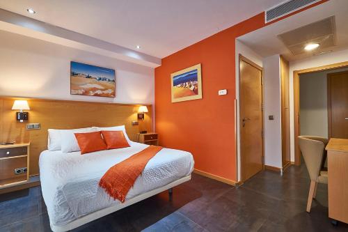 Habitación de hotel con cama y pared de color naranja en Hotel Real de Illescas, en Illescas
