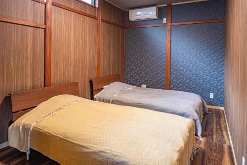 two beds in a room with wood paneling at La-gum - Vacation STAY 42137v in Inatori