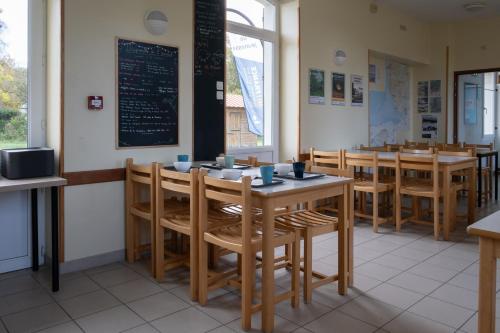 uma sala de jantar com mesas e cadeiras e um quadro-negro em Auberge de Jeunesse HI Genêts em Genêts