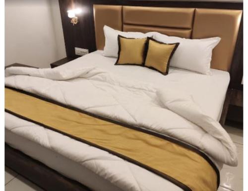 a large bed with white sheets and yellow pillows at Hotel Shere Punjab, Abu Road, RJ in Ābu Road