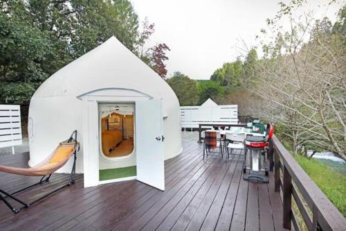a white house with a table and chairs on a deck at ASOGUNI Glamping - Vacation STAY 22084v in Oguni
