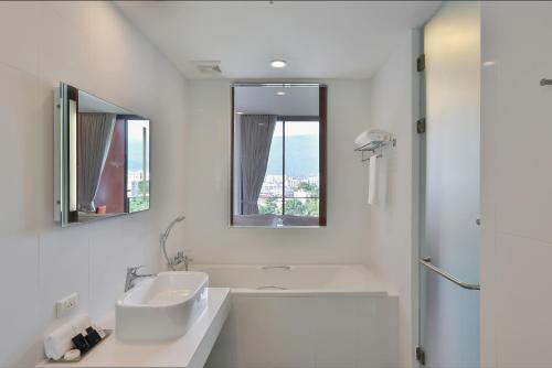 a white bathroom with a sink and a shower at Eastin Tan Hotel Chiang Mai in Chiang Mai