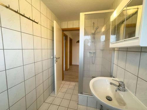 a white bathroom with a sink and a shower at Haus Glücksfang in Hooksiel in Wangerland