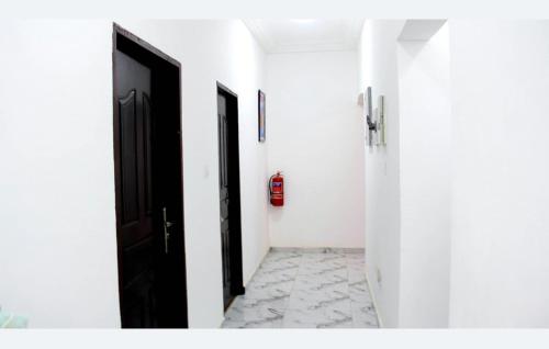 a hallway with two black doors and a tile floor at Tropical Oasis in Accra - 2 Bedroom Apartment in Accra