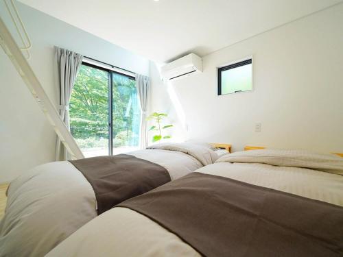 sypialnia z 3 łóżkami i oknem w obiekcie SENKO TINY CAMP - Vacation STAY 85298v w mieście Ueda