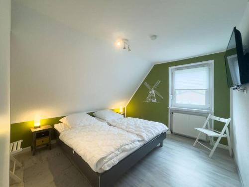 a bedroom with a bed and a window and a television at Haus Glücksfang in Hooksiel in Wangerland