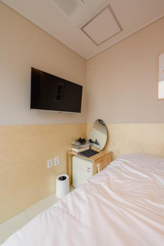 a bedroom with a bed and a flat screen tv on the wall at Hithere City Myeongdong in Seoul