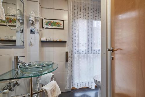 y baño con lavabo de cristal y aseo. en Hotel Real de Illescas, en Illescas