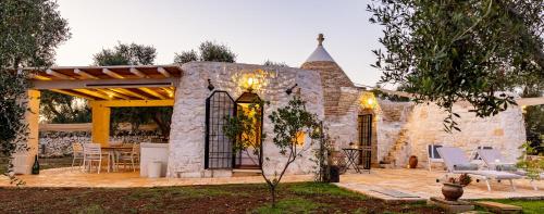 a stone house with a patio with a table and chairs at Trullo Cinderella mit Mountainbike & Pool in Martina Franca