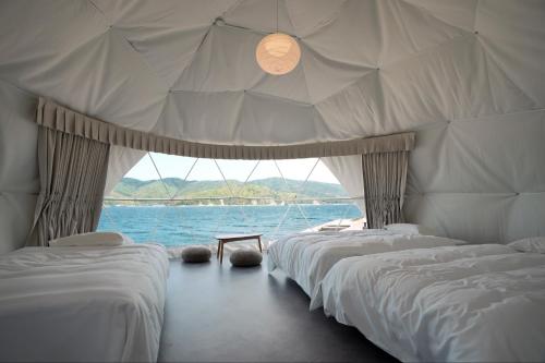 eine Reihe von Betten in einem Raum mit dem Wasser in der Unterkunft TADAYOI - Sea Glamping - Vacation STAY 42100v in Hishi