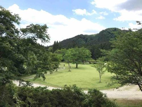 Nasu Takahara Auto Campsite - Vacation STAY 42064v في ناسوشيوبارا: حقل أخضر مع الأشجار والجبال في الخلفية