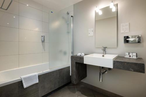 a bathroom with a sink and a shower and a mirror at Martin's Klooster in Leuven